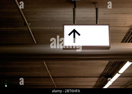 White light signs with black arrows installed on the top of the parking lot. Stock Photo