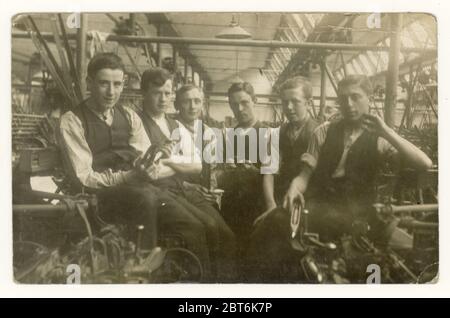 Original early 1900's postcard of group of young male cotton mill workers sitting next to loom machines, showing interior interiors of mill one of the lads is holding a 'flying shuttle' suggesting they are weavers, Blackburn, Lancashire, North West England, U.K. circa 1905