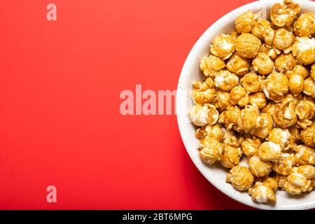 Plate with caramel popcorn on a red background, top view. Place for text Stock Photo