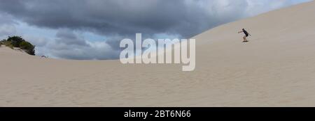 Kangaroo Island, Australia - March 9th, 2020: A panoramic view of a young man sand surfing under a cloudy sky. Stock Photo