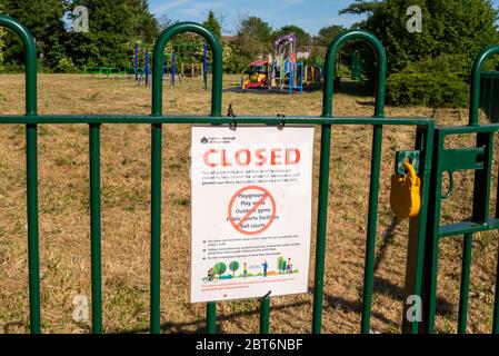 Closed park playground in Cranford, London, UK during COVID-19 Coronavirus lockdown. Shut and locked outside play area with warning sign on sunny day Stock Photo