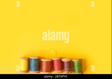 Colored coils with threads on a yellow background.Handicrafts and sewing. Stock Photo