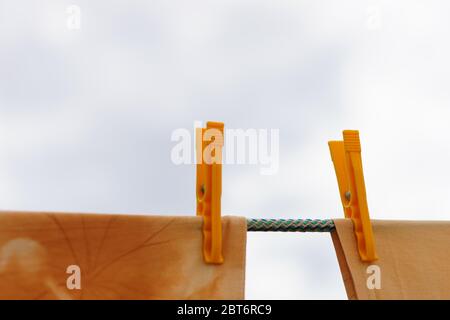 Beige clothes are dried with yellow plastic clothespins outdoors. Stock Photo