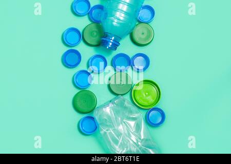 Composition of plastic bottles and plastic bottle caps on green background with space for text. Plastic free concept Stock Photo