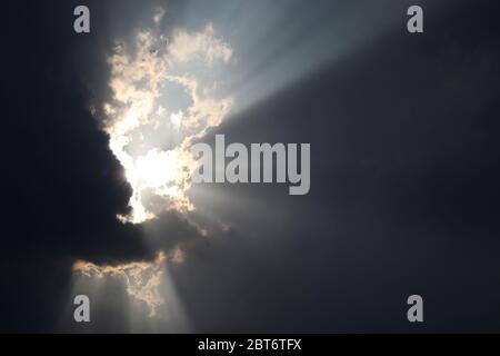 The light shone through from a dark cloud. The sun shines through the dark clouds. Stock Photo
