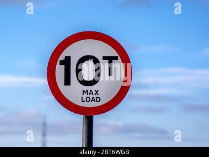 A round warning sign with a max load limit of 10 tonnes with a blue sky background. Stock Photo