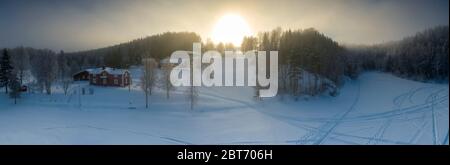 Majestic view of winter sunset with very large sun spot in frozen foggy air, winter pine tree forest, aerial, Grano village, around Umea city, Norther
