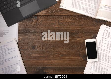 Remote education concept. Open books, smartphone and laptop on wooden desk background, flat lay Stock Photo