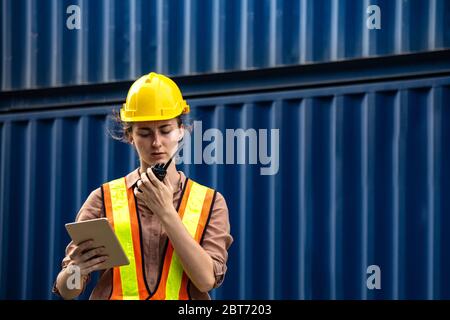 Female foreman is using walkie talkie and computer tablet to control work in industrial business Stock Photo