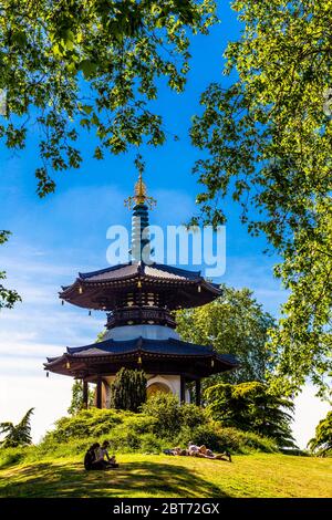 21 May 2020, London, UK - People relaxing the in sun in Battersea Park with the Peace Pagoda in the background during the Coronavirus pandemic lockdown Stock Photo