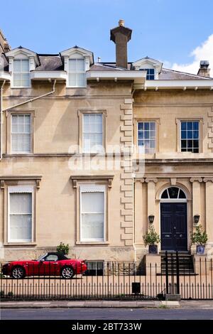 Beautiful Cotswold stone town house with iconic red sports car parked outside Stock Photo