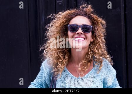 Joyful and happiness concept with cheerful beautiful adult caucasian woman smile and laugh in front of the camera and black wall in background - happy Stock Photo