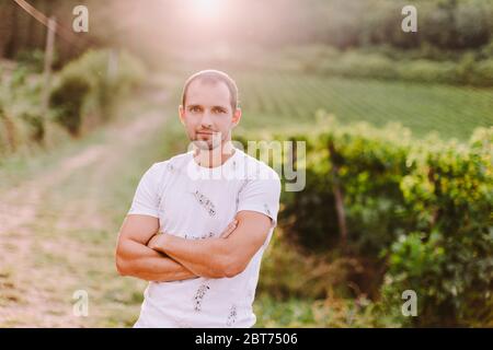 portrait of a man arms closed at the countryside. Handsome man in countryside vineyards looking at camera. Farm owner. Italy Stock Photo