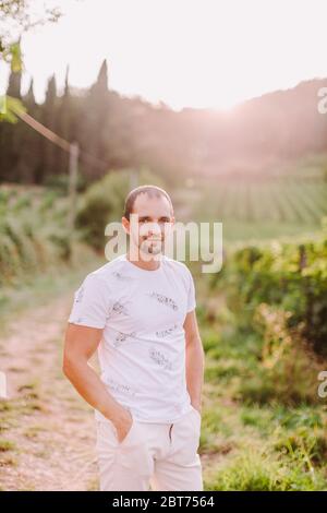 portrait of a man at the countryside at sunset. Handsome man in countryside vineyards looking at camera. Farm owner. Italy Stock Photo