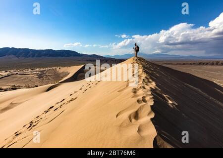 Man standing on top of sand dune Stock Photo