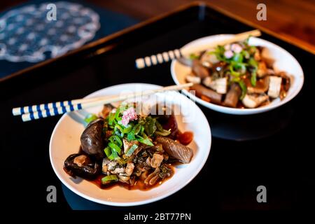 Traditional japanese house or ryokan restaurant with black lacquered wood table and food dish closeup of oden tofu mushrooms topped with pickled sakur Stock Photo