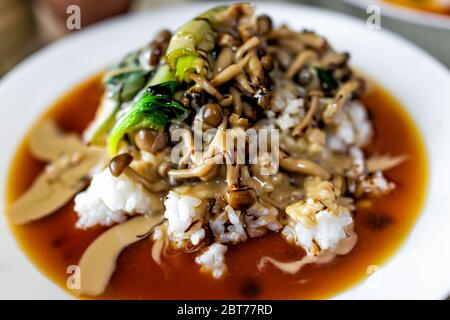 Traditional plate vegetable japanese dish in Japan with mushrooms and spinach greens on pile of white rice and soy sauce on white plate closeup Stock Photo