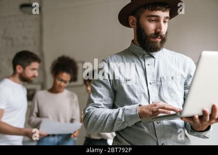 Image of multiethnic young business people working together at office. Man using laptop Stock Photo