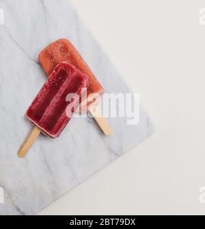 Raspberry and Strawberry popsicles on marble Stock Photo