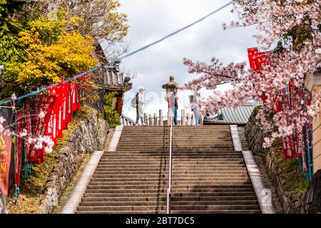 Nara, Japan - April 14, 2019: People at the top of steps stairs up with red flags banners to Kofuku-ji temple in downtown city Stock Photo