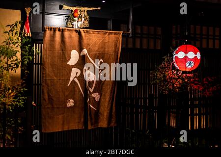 Kyoto, Japan - April 16, 2019: Alley street in Gion district at dark evening night with illuminated red lanterns paper lamps at entrance to izakaya re Stock Photo