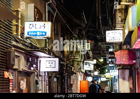 Tokyo, Japan - April 3, 2019: Shinjuku ward downtown with people on Golden Gai narrow alley lane street with izakaya restaurants at night and signs Stock Photo