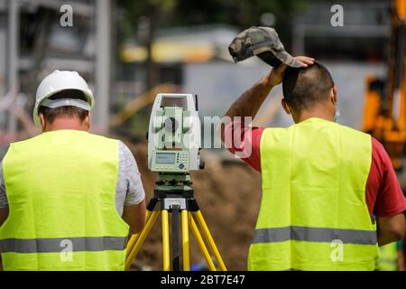 Bucharest, Romania - May 8, 2020: Topography engineers on a construction site with protective masks due to the Covid-19 outbreak. Stock Photo