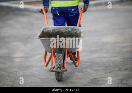 Details with a construction worker pulling a wheelbarrow on a construction site. Stock Photo