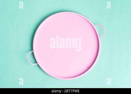 Flat lay view above blank round pink ceramic dish or pan for placement freshly cooked healthy food on a light turquoise background, copy space. Stock Photo