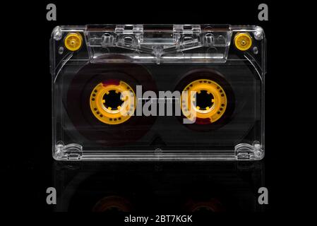 Audio cassette tape with yellow tape reels and tape guides on black background Stock Photo