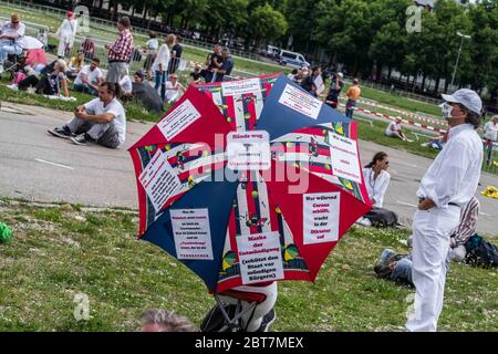 Munich, Bavaria, Germany. 23rd May, 2020. A woman holds an umbrella with many of the talking points of those against the Coronavirus measures. After days of back and forth wrangling with the Munich Kreisverwaltungsreferat, the organizers of the so-called 'Hygiene Demo'' in Munich were again granted permission for 1,000 distanced participants inside the demo area only to have torrential downpours and dangerous winds cause a cancellation for the 500 that arrived.Further being criticized by politicians, civic groups and healthcare workers are the words of 'no violence'' for the previous dem Stock Photo