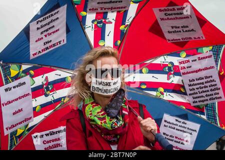 Munich, Bavaria, Germany. 23rd May, 2020. A woman holds an umbrella with many of the talking points of those against the Coronavirus measures and ''Mask of Prohibition (of speech) on her mouth. After days of back and forth wrangling with the Munich Kreisverwaltungsreferat, the organizers of the so-called 'Hygiene Demo'' in Munich were again granted permission for 1,000 distanced participants inside the demo area only to have torrential downpours and dangerous winds cause a cancellation for the 500 that arrived.Further being criticized by politicians, civic groups and healthcare workers are Stock Photo