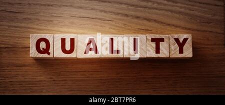 Word QUALITY on wooden cubes on wood background. Evaluation of good or services business concept Stock Photo