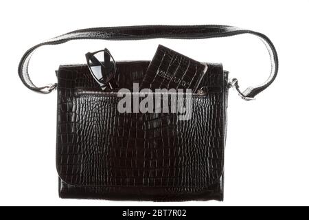 Sunglasses and passport stick out of the pocket of a black bag handbag isolated on a white background. Travel and vacation Stock Photo