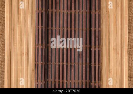 Dark and light bamboo mat in the form of a scroll lie on the burlap. Top view Stock Photo