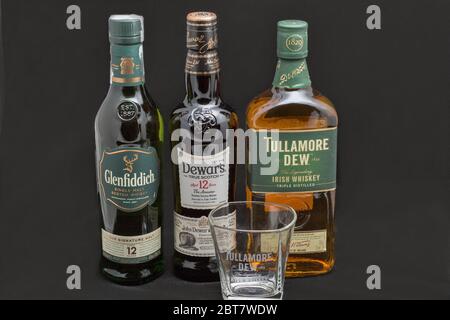 KYIV, UKRAINE - AUGUST 17, 2019: Bottles of Glenfiddich, Dewars and Tullamore DEW Scotch and Irish single malt and blended whisky against black backgr Stock Photo