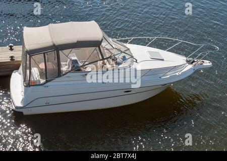 Luxury boat moored on a sunny day, view from above. Wooden pier at river with rope and mooring post. Stock Photo