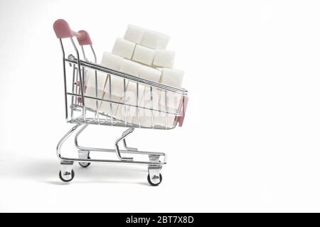 Shopping cart is filled with refined sugar cubes on a white background Stock Photo