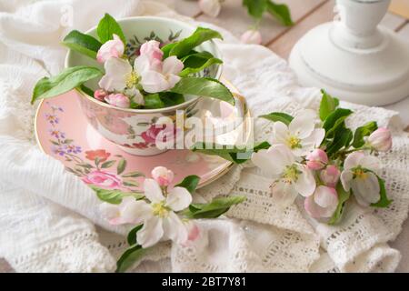 handmade lace on shabby chic and pink retro mug with white flowers. Macrame closeup. Wedding or holiday background. Stock Photo