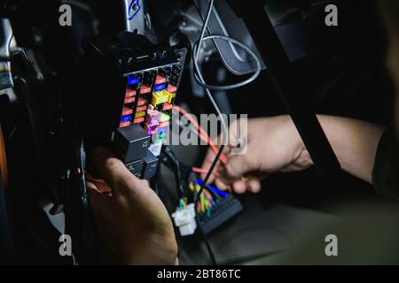 car fuse box and hands holding wires at shallow depth of field Stock Photo