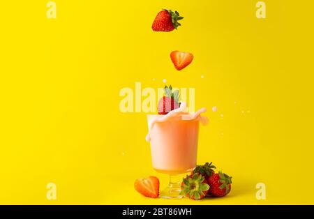 splashing splash strawberry juice smoothies and strawberries on yellow background as healthy detox diet drinks Stock Photo