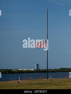 Cape Canaveral, Florida, USA. 22nd May, 2020. The American flag flies at half-staff next to the countdown clock at NASA's Kennedy Space Center Press Site, on May 22, 2020, in Florida. President Donald Trump directed on Thursday that flags be lowered to half-staff until sunset on May 24th 'as a mark of solemn respect for the victims of the coronavirus pandemic.' NASA's SpaceX Demo-2 mission is the first launch with astronauts of the SpaceX Crew Dragon spacecraft and Falcon 9 rocket to the International Space Station as part of the agency's Commercial Crew Program. Credit: UPI/Alamy Live News Stock Photo