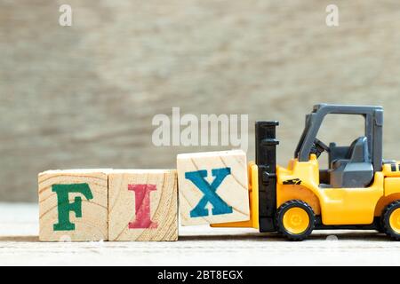 Toy forklift hold letter block x to complete word fix on wood background Stock Photo