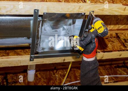 Worker installing new air conditioner vents in new home construction Stock Photo