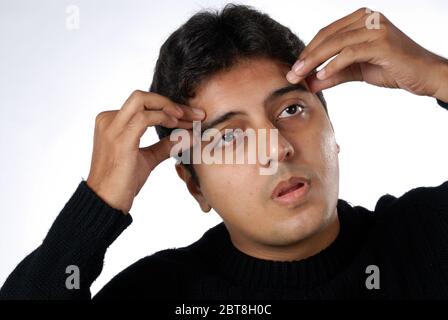 Mumbai Maharashtra India Indian asian Young man suffering from severe headache; pressing fingers to temples; pain with helpless face expression Stock Photo