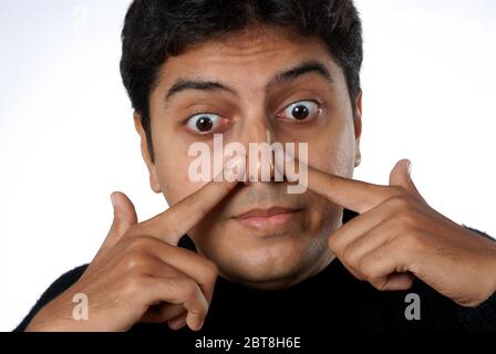 Mumbai Maharashtra India Asia Sep. 24, 2007 - Indian asian Frustrated young man suffering from sinus pressure, touching his nose on white background Stock Photo