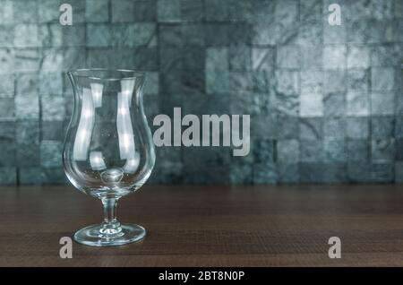 Empty stylish beer glass on wooden table and stone background. Stock Photo