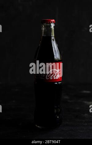 glass bottle of Coca-cola carbonated drink, with a red label on a dark background Stock Photo
