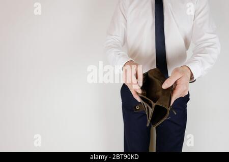 A man in a business suit holds in his hands an empty wallet without money. Financial crisis. Bankruptcy in business. The employer is disappointed. Stock Photo