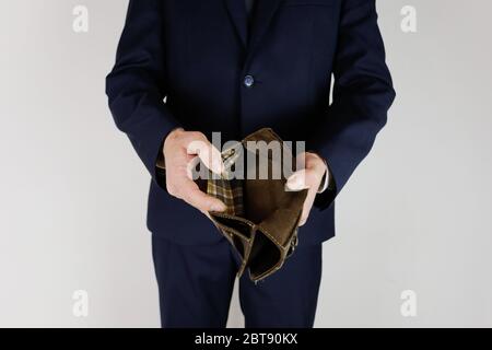 A man in a business suit holds in his hands an empty wallet without money. Financial crisis. Bankruptcy in business. The employer is disappointed. Stock Photo